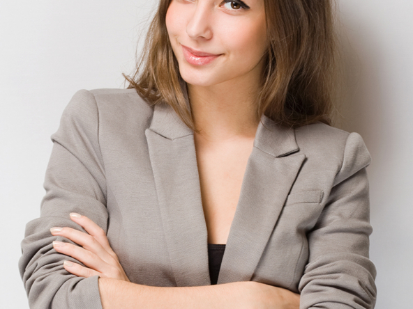 Confident woman in a beige blazer with arms crossed smiling.