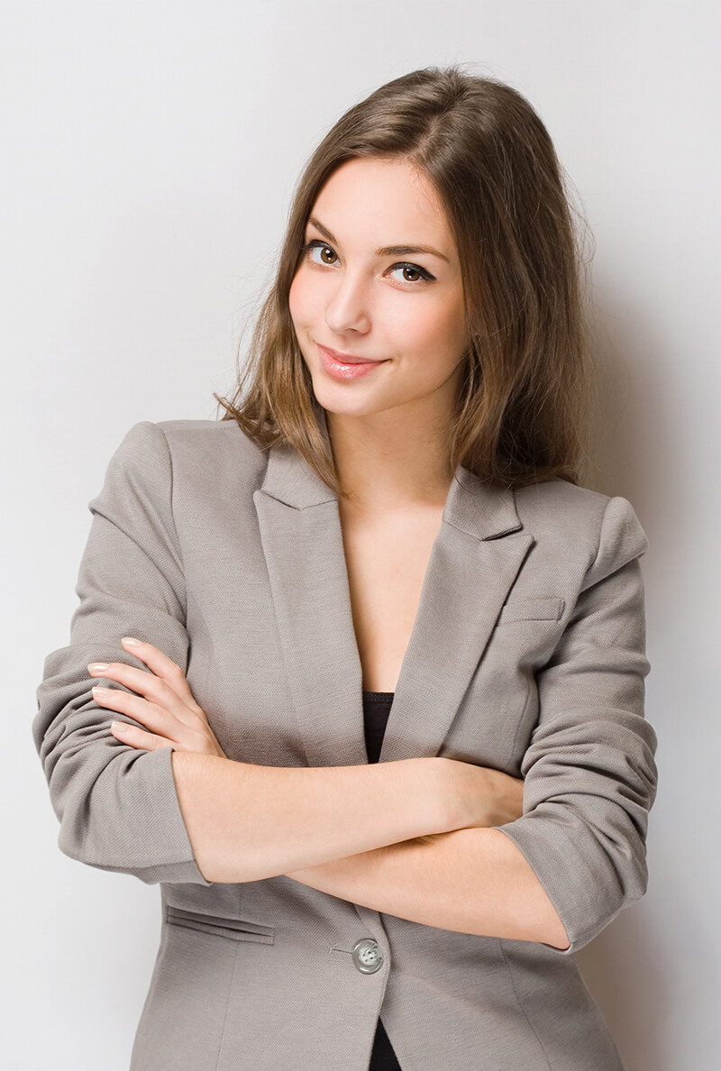 Confident woman in a beige blazer with arms crossed smiling.
