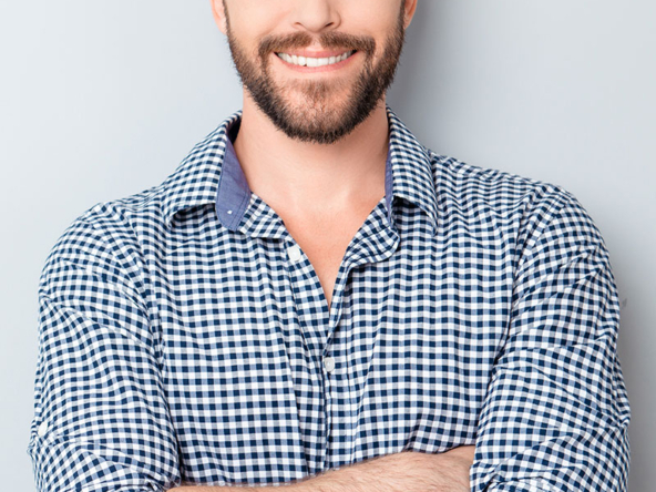 Smiling man in a checkered shirt with arms crossed.