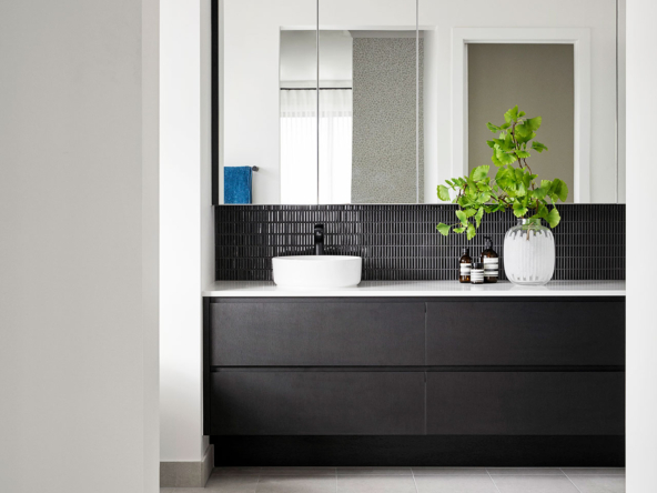 Modern bathroom vanity with black tiles and white basin.