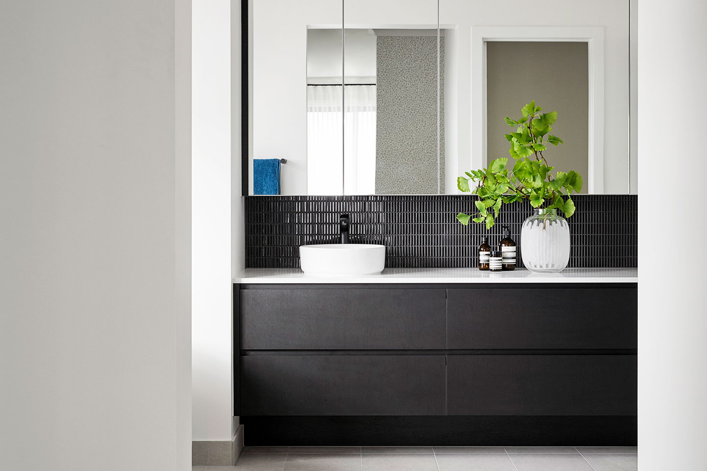 Modern bathroom vanity with black tiles and white basin.