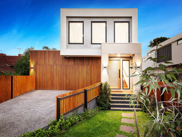 Modern two-story house with wooden accents and a landscaped front yard.