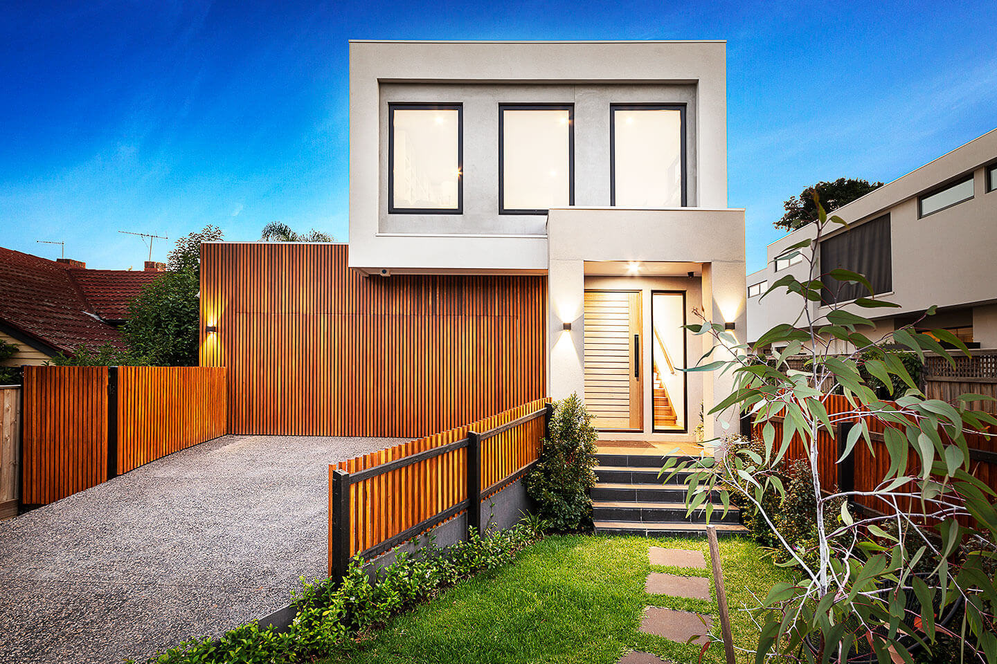 Modern two-story house with wooden accents and a landscaped front yard.