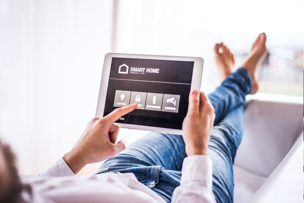 Person using a tablet to browse a smart home app while sitting comfortably.