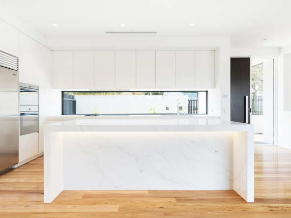Modern kitchen island with white marble and wooden flooring.