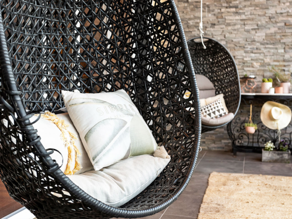 Cozy hanging wicker chair with cushions in a stylish indoor setting.