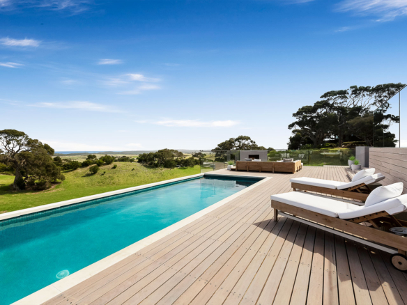 Modern outdoor pool with loungers and scenic green landscape.