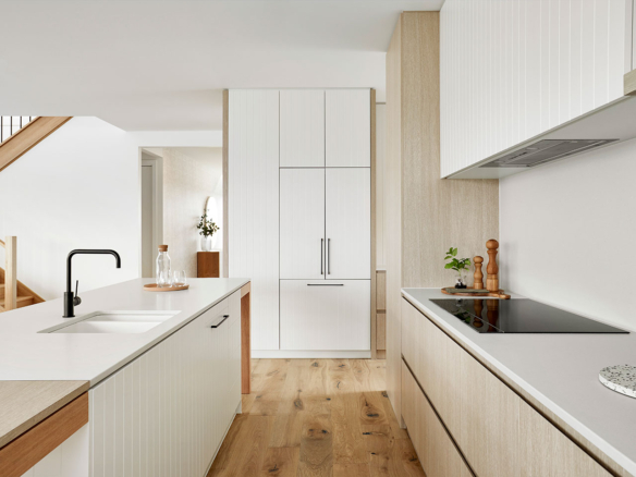 Bright modern kitchen with white cabinets and wood accents.