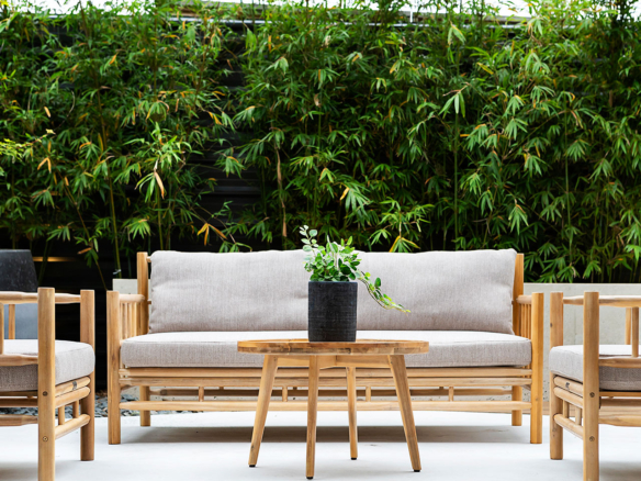 Minimalist outdoor seating area with wooden furniture and greenery.