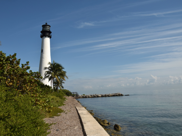A lighthouse stands tall near a calm sea under a blue sky.