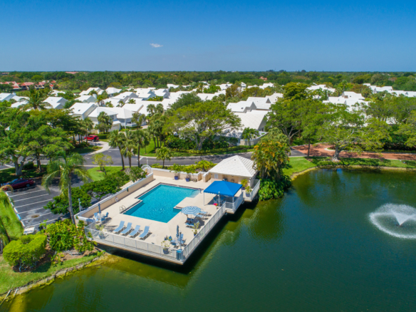 Scenic waterfront pool area with lounge chairs and umbrellas.