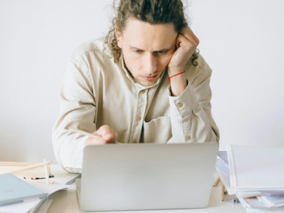 A man focused on his laptop with papers around him.