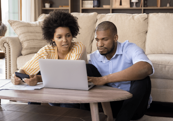 Couple using a laptop together on a coffee table.