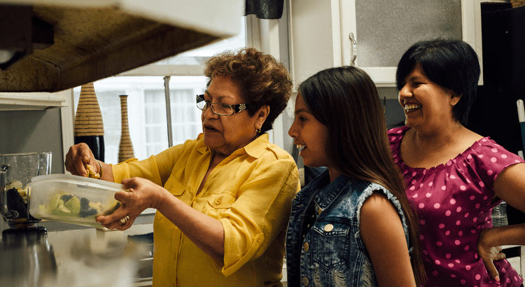 An elderly woman teaching a young girl how to knit indoors.