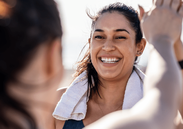 A joyful woman smiling with a towel around her neck.