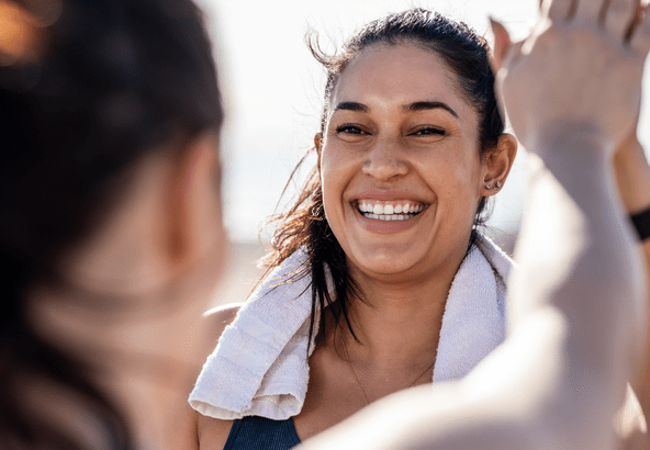 A joyful woman smiling with a towel around her neck.