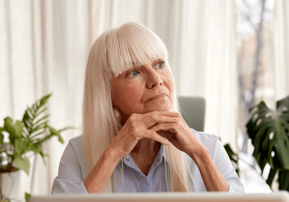 Thoughtful elderly woman with white hair gazing out the window.