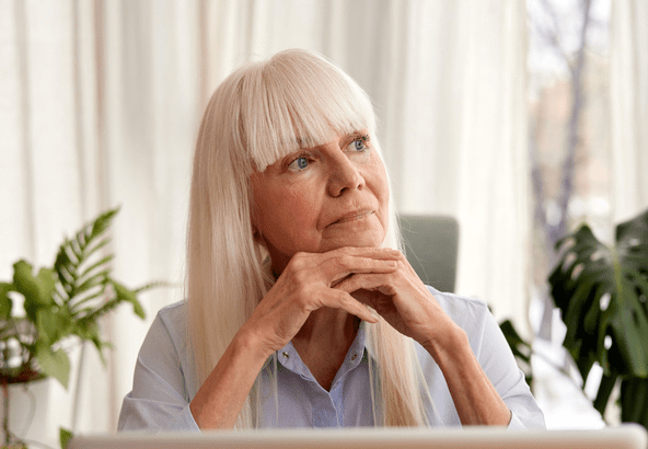 Thoughtful elderly woman with white hair gazing out the window.