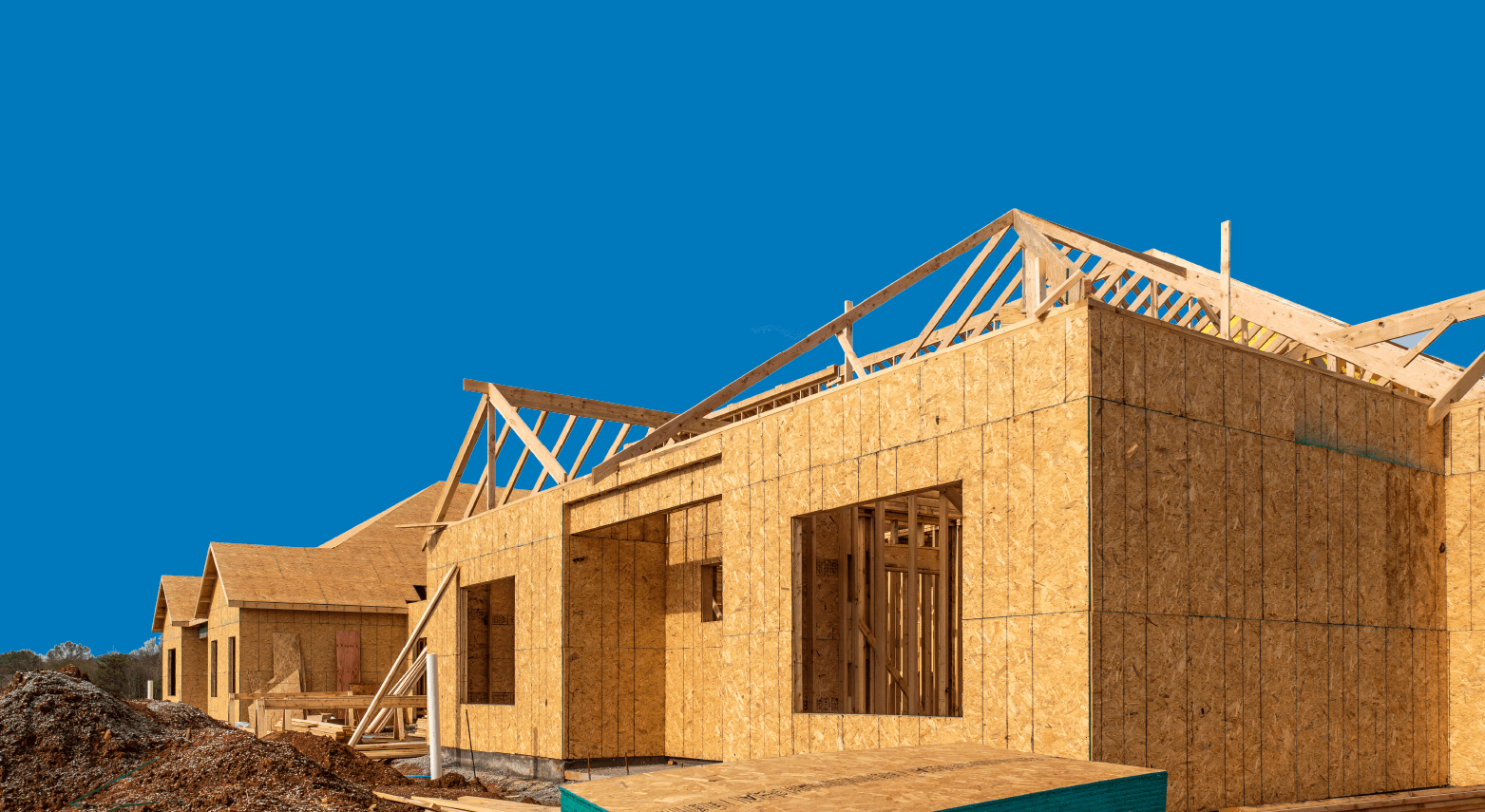 Wooden frame of a house under construction against a clear blue sky.