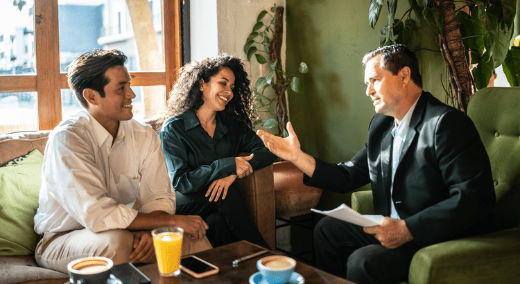 Three people engaged in a lively discussion over coffee in a cozy setting.