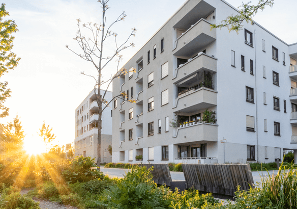 Modern apartment buildings during sunset with greenery around.