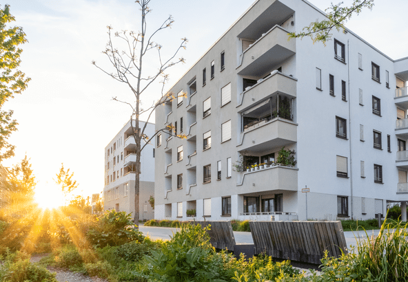 Modern apartment buildings during sunset with greenery around.