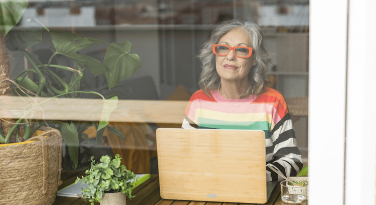 Woman with laptop, colorful sweater, red glasses.