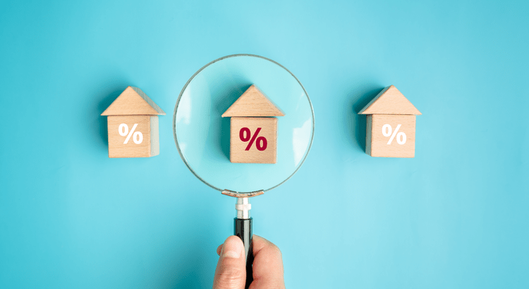 Magnifying glass over wooden house with percentage.