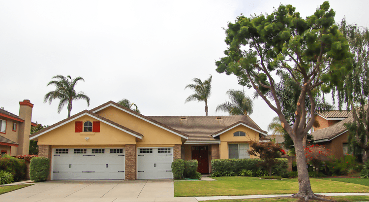 Suburban house with palm trees and driveway.