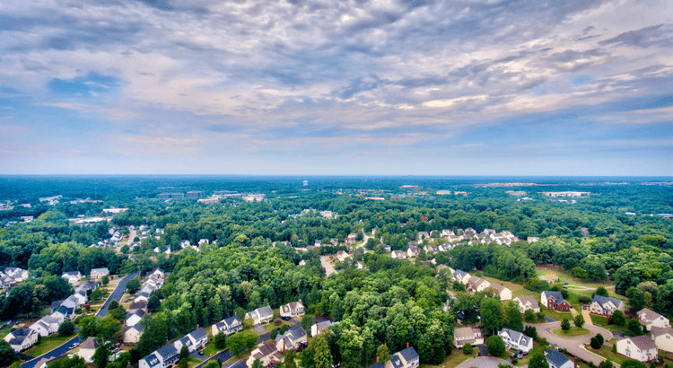 Suburban neighborhood with trees and cloudy sky.