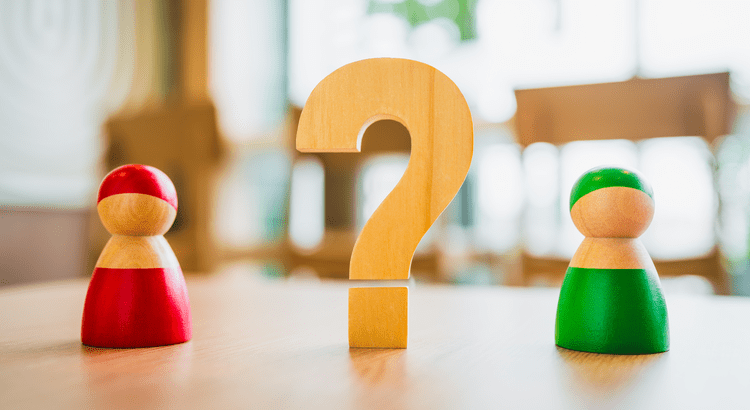 Wooden figures with question mark between them.