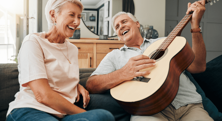 Elderly couple laughing with a guitar.