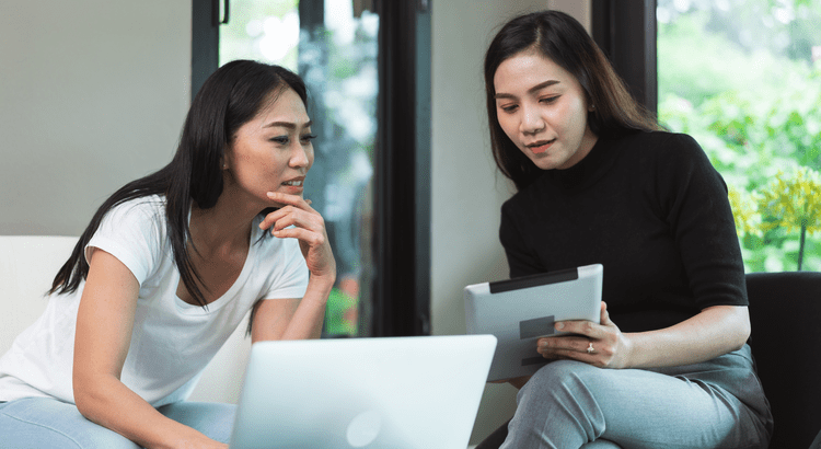 Two women discussing work on laptop.