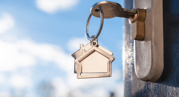 Key with house keychain in door.