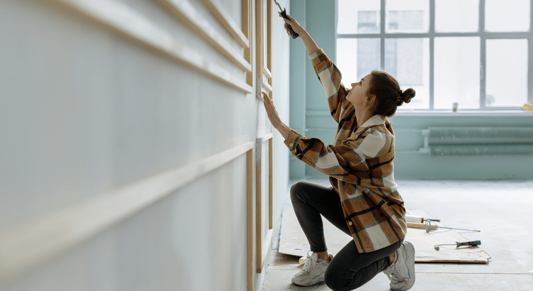 Woman measuring wall with tape measure indoors.