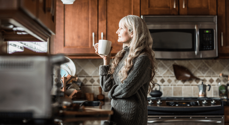 Woman drinking coffee in a kitchen.